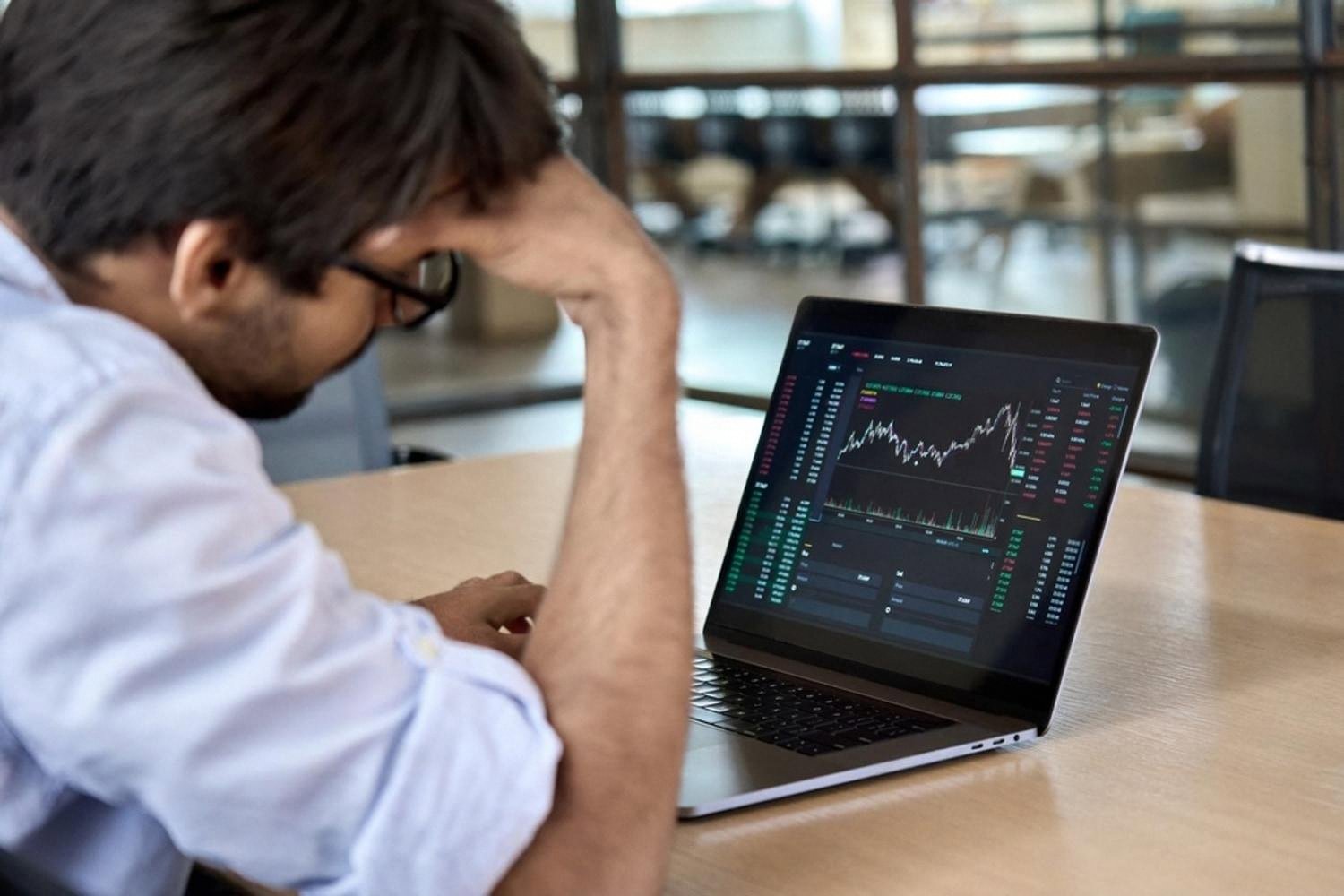 Businessman looking stressed at a laptop showing financial losses caused by a bad vendor